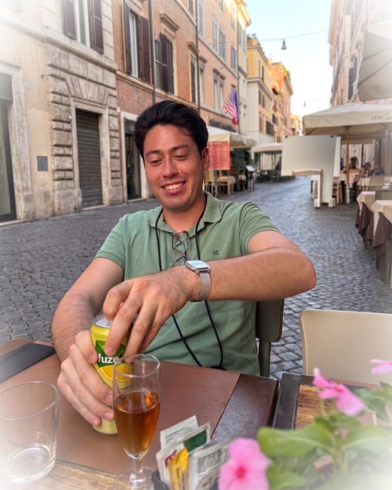 Guillermo sentado en una terraza de una calle de Roma, sonriendo